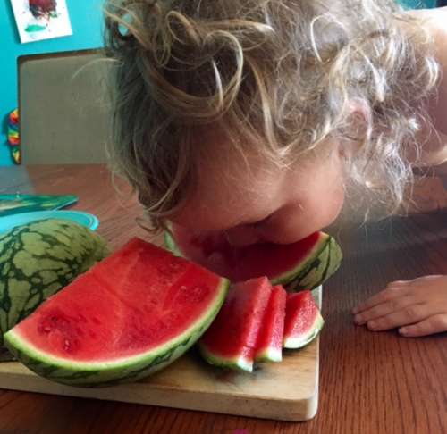 Goofy girl couldn't wait for me to finish slicing the watermelon.