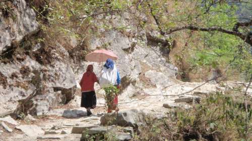 An elderly woman and a younger woman trekking between villages.