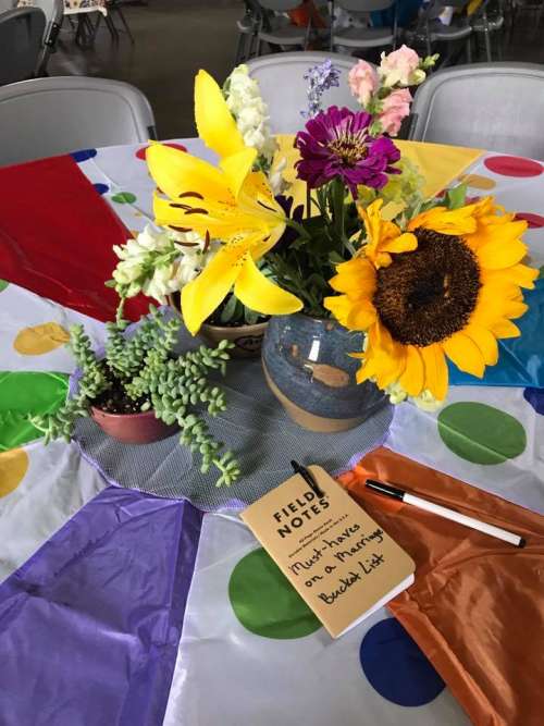 The table decor: Parachute table cloth, farmers market flowers in hand thrown vases, succulents in hand thrown pots and a "guest book" at each table.