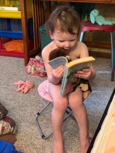 Opal reading a Little House book to her stuffed animals.  