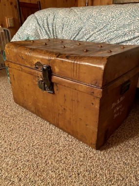 An antique, metal shipping trunk adds chic vintage style with lots of storage in Andrea’s lakehouse guest room. 