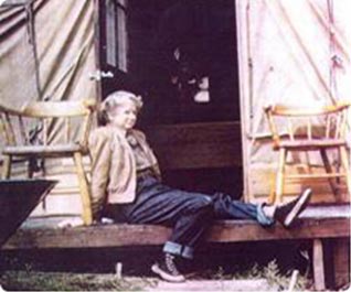 Louise Kellogg sitting on the deck of her Wall Tent